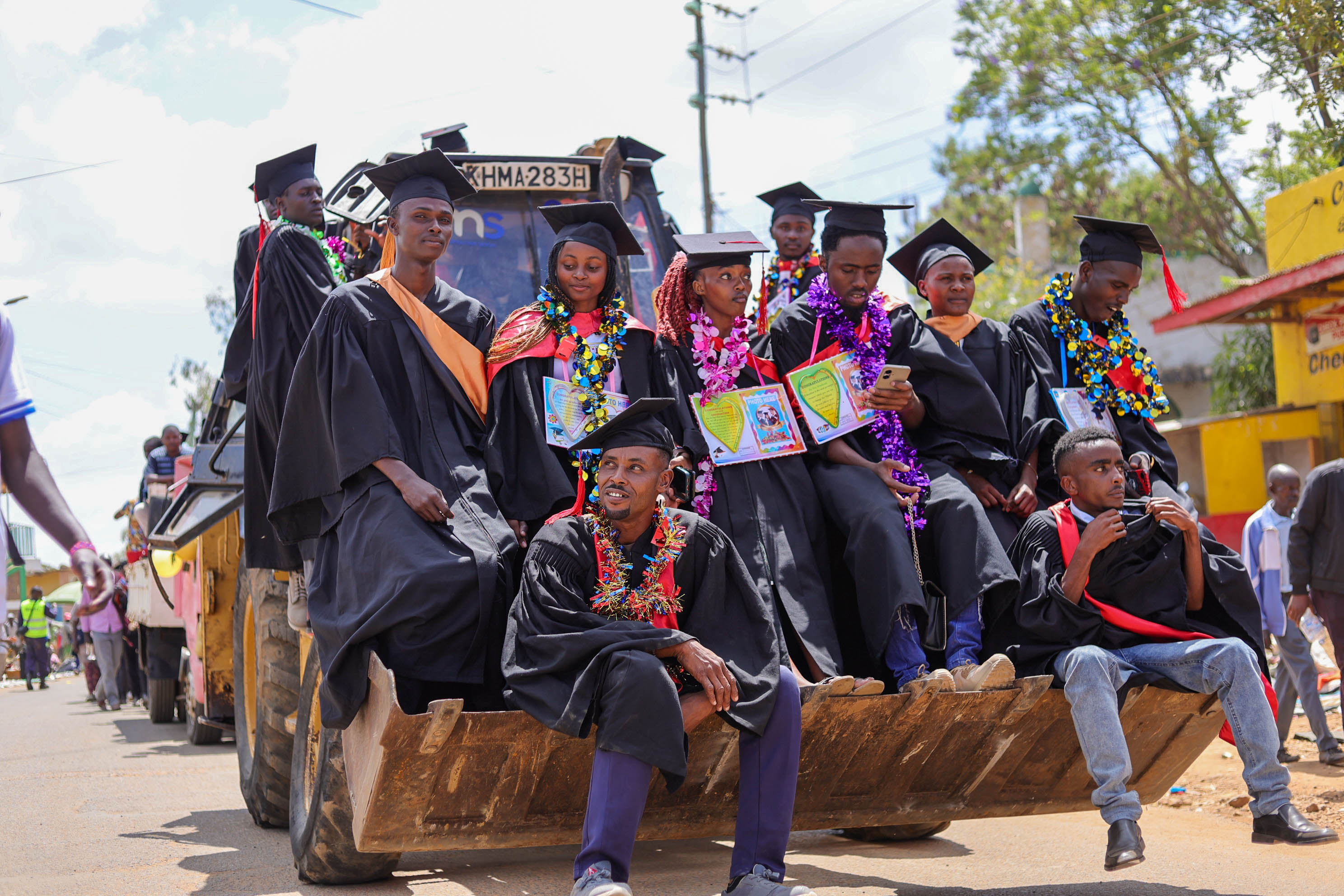 Backhoe carrying graduating students | KIPEM